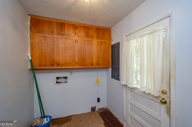 clothes washing area with hookup for a washing machine, a textured ceiling, cabinets, and electric panel