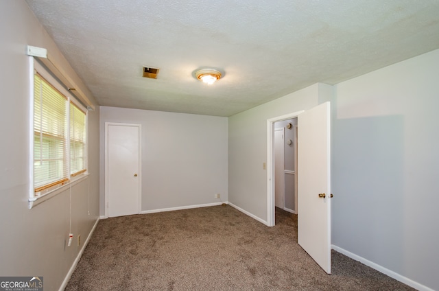 spare room featuring carpet flooring and a textured ceiling