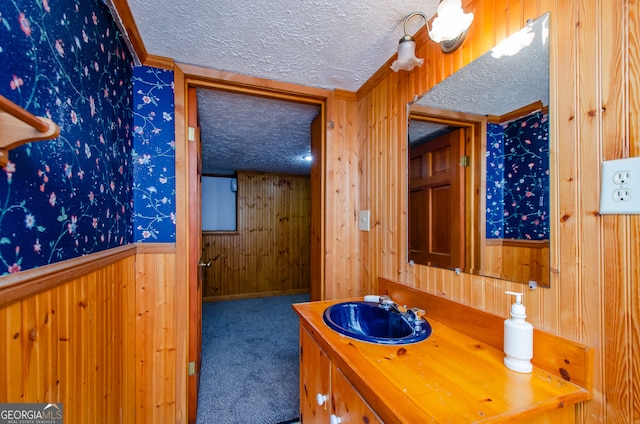 bathroom with vanity, wood walls, and a textured ceiling