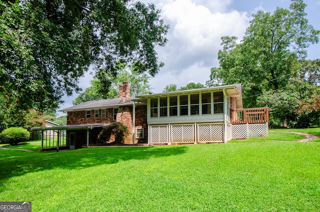 rear view of house with a wooden deck, a sunroom, and a yard