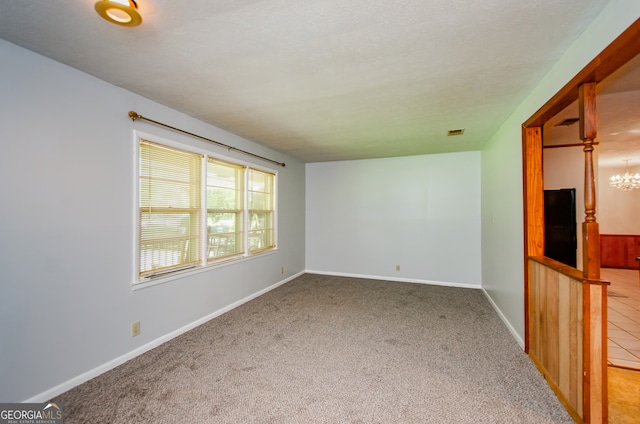 carpeted spare room featuring a chandelier