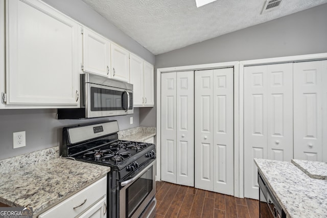 kitchen with visible vents, light stone counters, dark wood-style flooring, stainless steel appliances, and white cabinetry