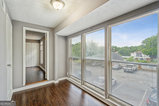 doorway with visible vents, baseboards, dark wood finished floors, and a textured ceiling