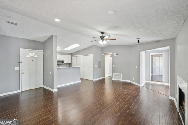 unfurnished living room featuring a ceiling fan, a textured ceiling, visible vents, and dark wood-style flooring