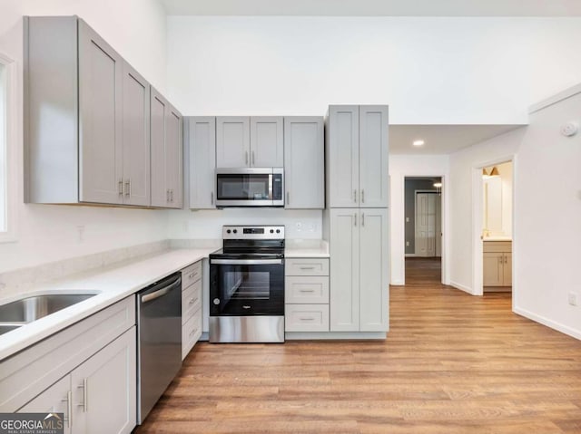 kitchen with gray cabinetry, sink, stainless steel appliances, and light hardwood / wood-style floors