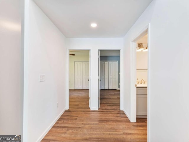 corridor with hardwood / wood-style flooring and sink