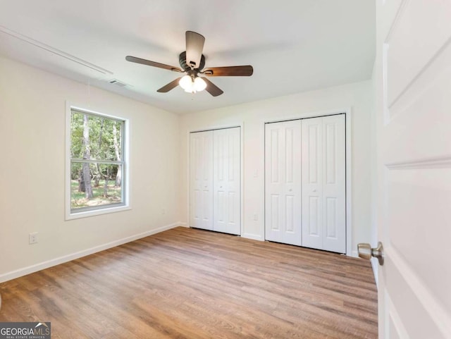 unfurnished bedroom featuring ceiling fan, light hardwood / wood-style flooring, and two closets