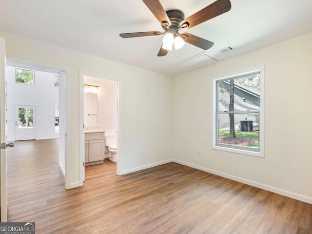 unfurnished bedroom with ceiling fan, light wood-type flooring, and connected bathroom