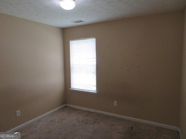 carpeted spare room with a textured ceiling