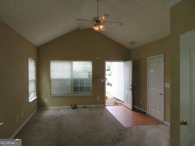 carpeted spare room with ceiling fan, plenty of natural light, and vaulted ceiling