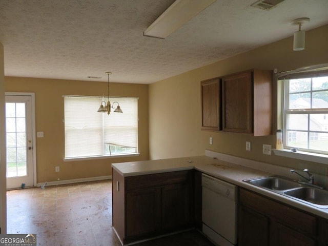 kitchen with sink, white dishwasher, a healthy amount of sunlight, decorative light fixtures, and kitchen peninsula