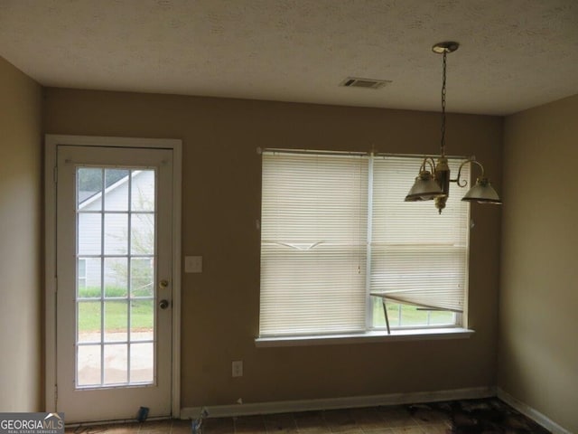 unfurnished dining area with plenty of natural light and a textured ceiling