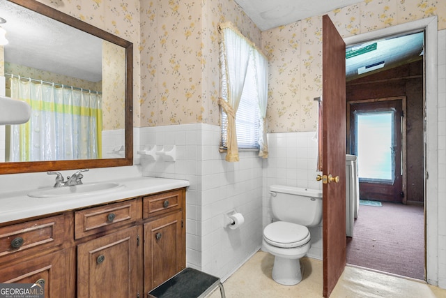 bathroom featuring toilet, a healthy amount of sunlight, vanity, and tile walls