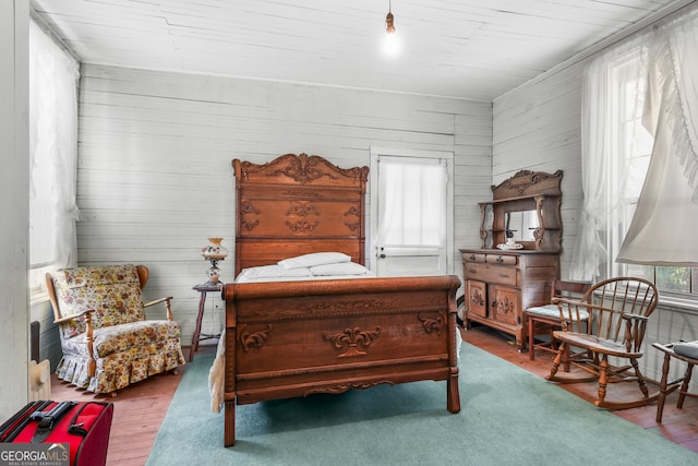 bedroom with wood walls and hardwood / wood-style floors