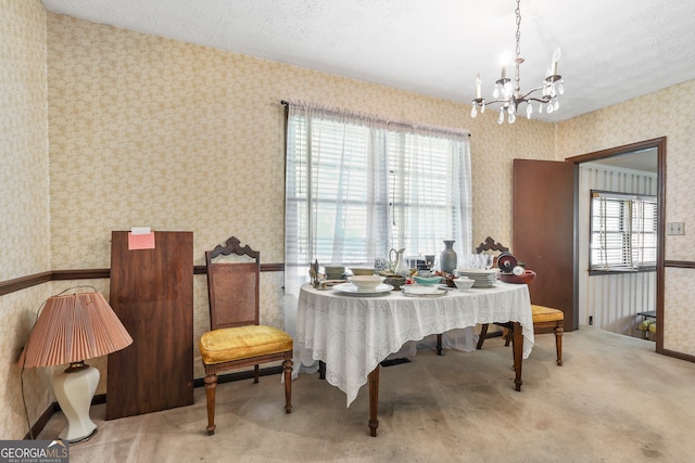 carpeted dining room with a notable chandelier and a textured ceiling