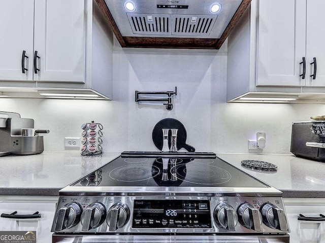 kitchen with crown molding, stove, and white cabinetry