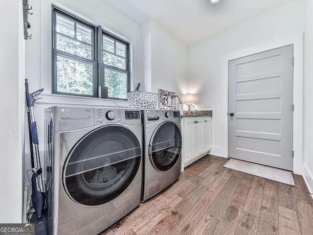 laundry area featuring cabinets, hardwood / wood-style floors, washer and clothes dryer, and sink