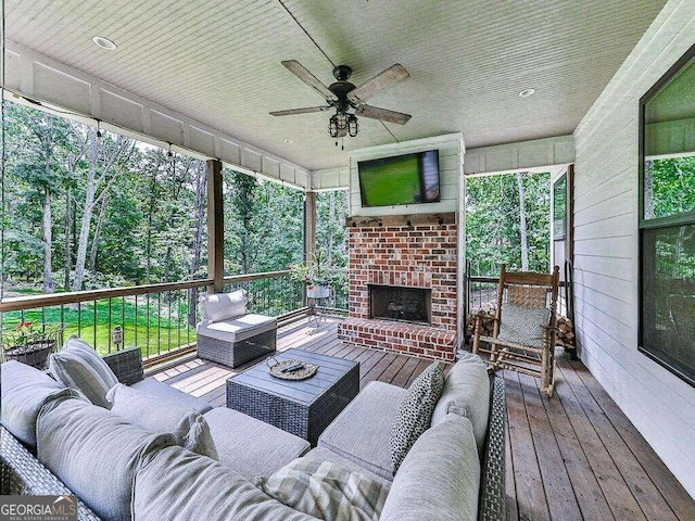 wooden terrace featuring ceiling fan and an outdoor living space with a fireplace