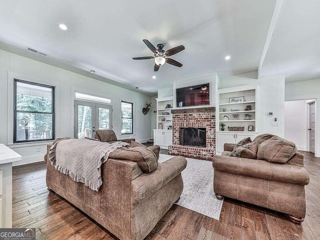 living room with a fireplace, dark hardwood / wood-style flooring, french doors, built in features, and ceiling fan