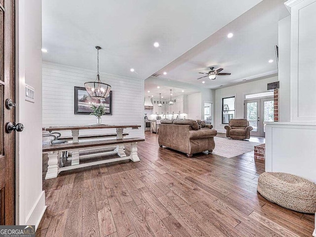 interior space featuring ceiling fan with notable chandelier, french doors, and wood-type flooring