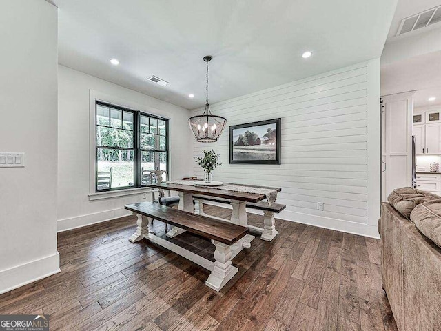 dining room featuring dark hardwood / wood-style floors, an inviting chandelier, and wood walls