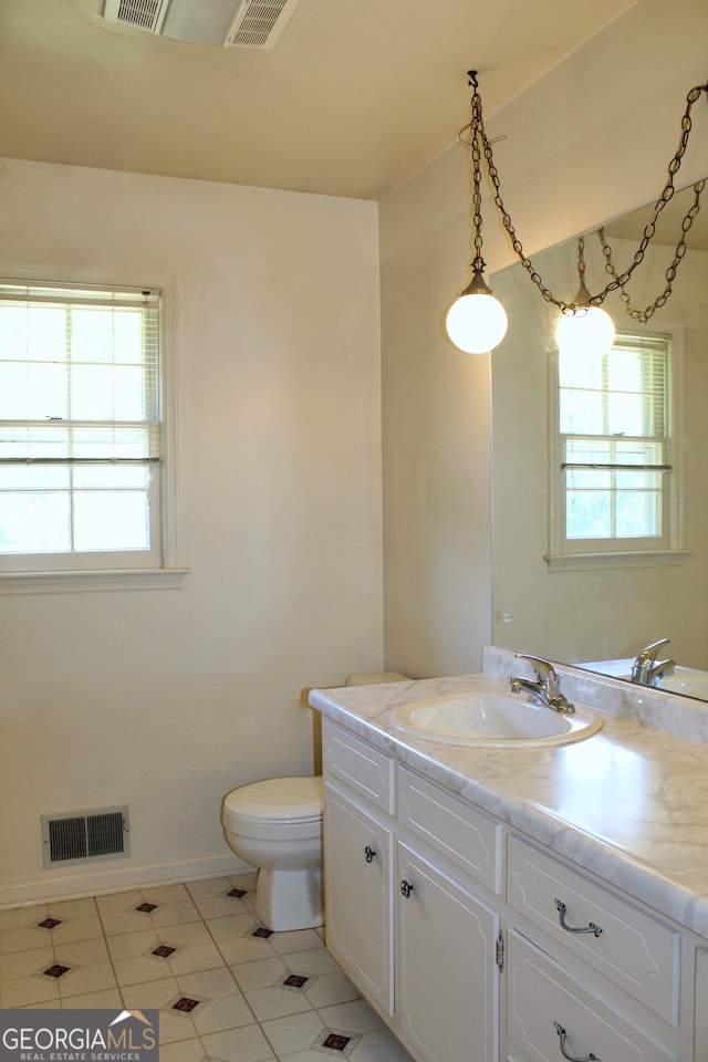 bathroom with tile patterned flooring, plenty of natural light, vanity, and toilet