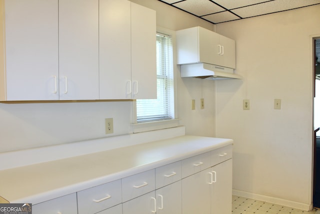 kitchen with custom range hood, white cabinetry, and light tile patterned floors