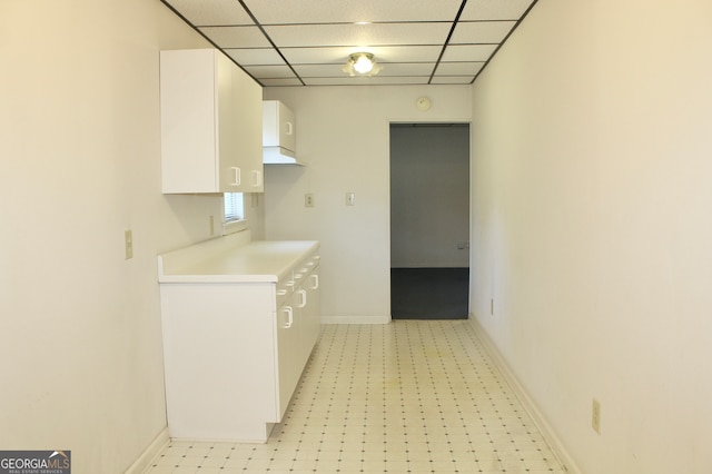 kitchen with a paneled ceiling, light tile patterned flooring, and white cabinets