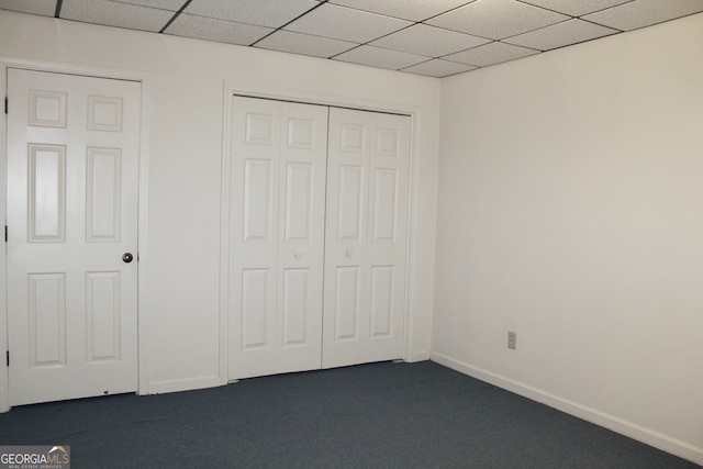 unfurnished bedroom featuring a closet, carpet floors, and a drop ceiling