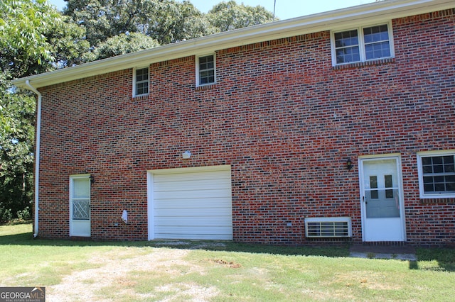 back of house featuring a garage and a lawn