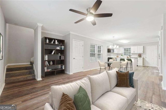 living room featuring ornamental molding, hardwood / wood-style flooring, and ceiling fan with notable chandelier