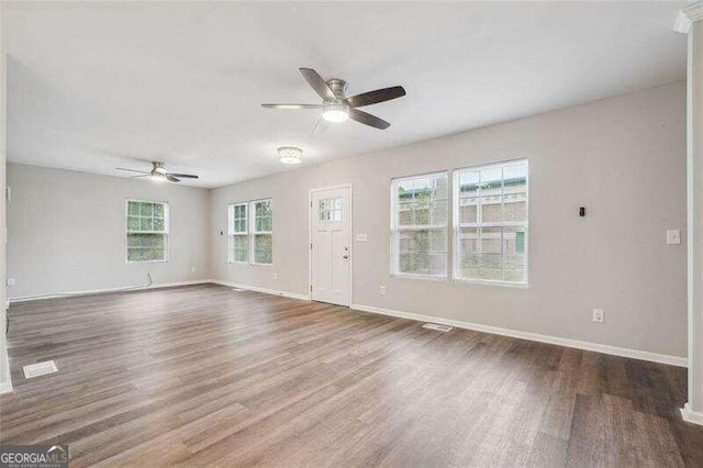 spare room with ceiling fan, wood-type flooring, and a healthy amount of sunlight