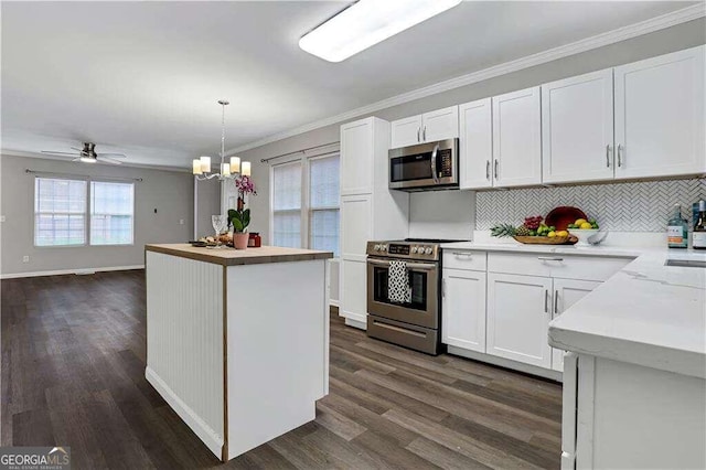 kitchen with white cabinets, appliances with stainless steel finishes, a kitchen island, and pendant lighting