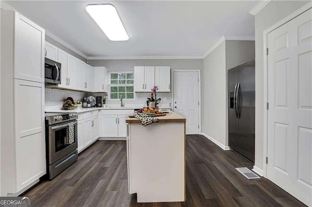 kitchen featuring white cabinetry, a kitchen island, stainless steel appliances, and wooden counters