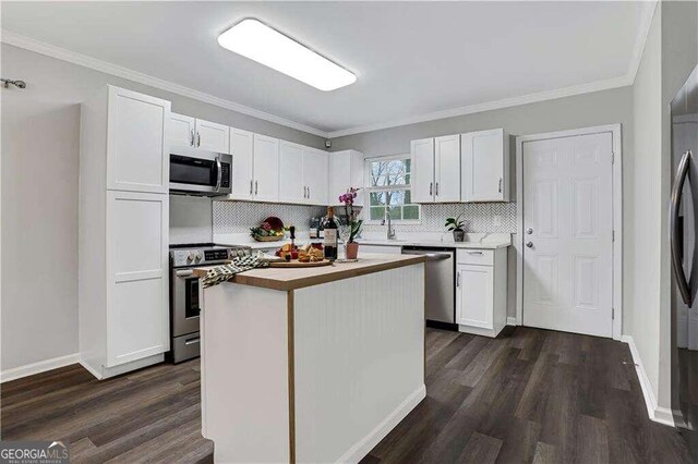 kitchen with dark hardwood / wood-style flooring, stainless steel appliances, a kitchen island, and white cabinetry