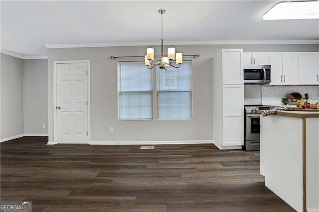 kitchen with hanging light fixtures, dark wood-type flooring, stainless steel appliances, white cabinets, and crown molding