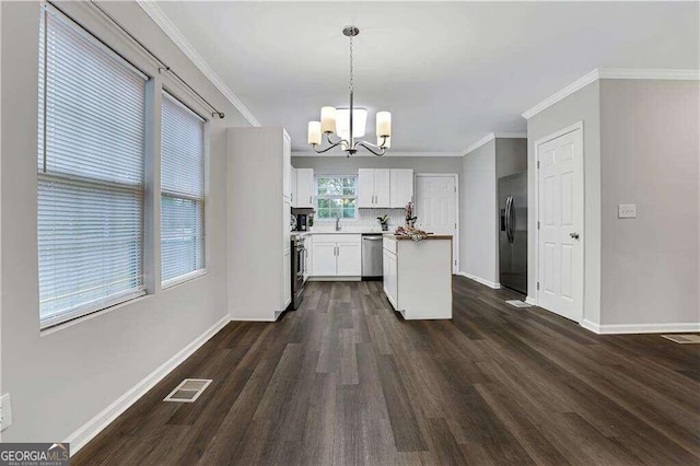 kitchen with hanging light fixtures, dark hardwood / wood-style floors, appliances with stainless steel finishes, white cabinets, and a notable chandelier