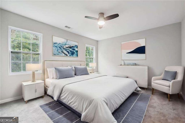 carpeted bedroom with multiple windows and ceiling fan