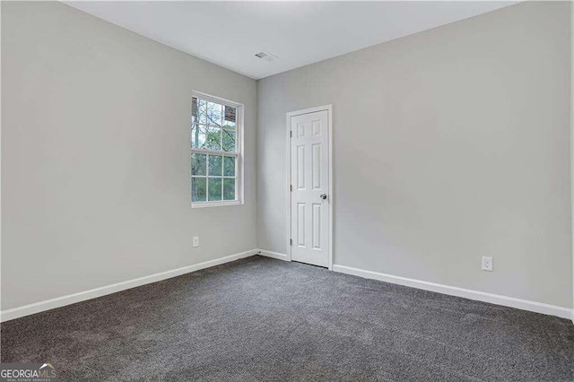 spare room featuring dark carpet