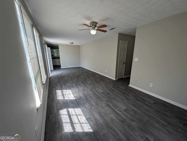 empty room featuring a textured ceiling, ceiling fan, and dark wood-type flooring