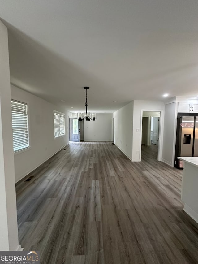 unfurnished living room with wood-type flooring and an inviting chandelier