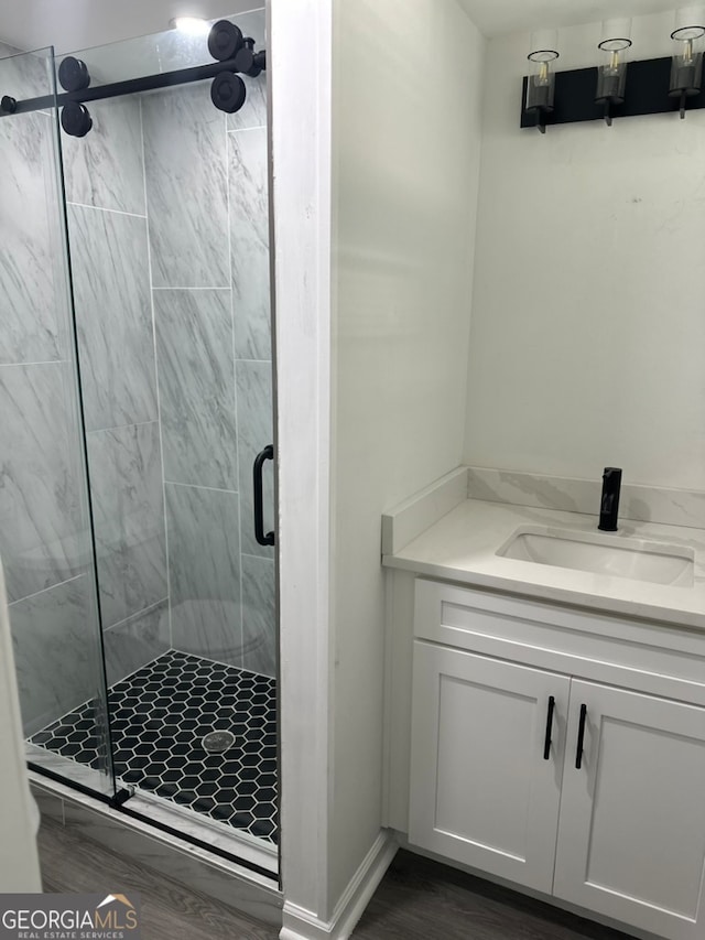 bathroom with wood-type flooring, vanity, and a shower with shower door