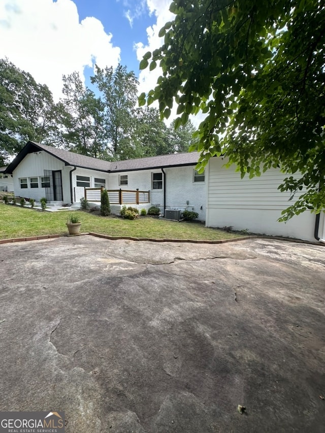 ranch-style house with a front yard and central AC unit