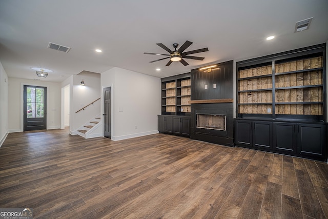 unfurnished living room featuring ceiling fan and dark wood-type flooring