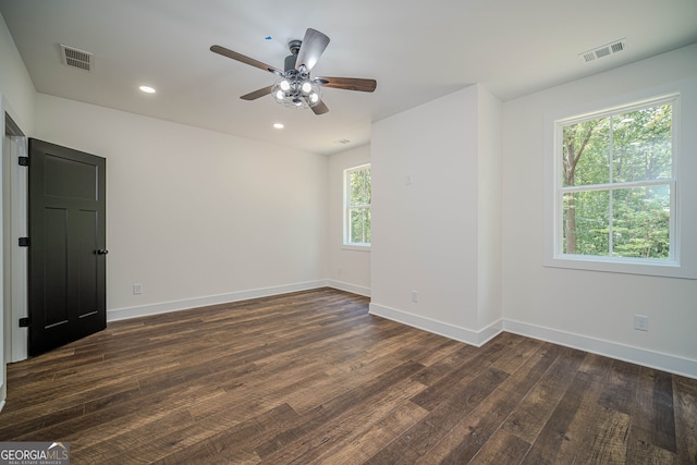 empty room featuring ceiling fan, a healthy amount of sunlight, and dark hardwood / wood-style floors