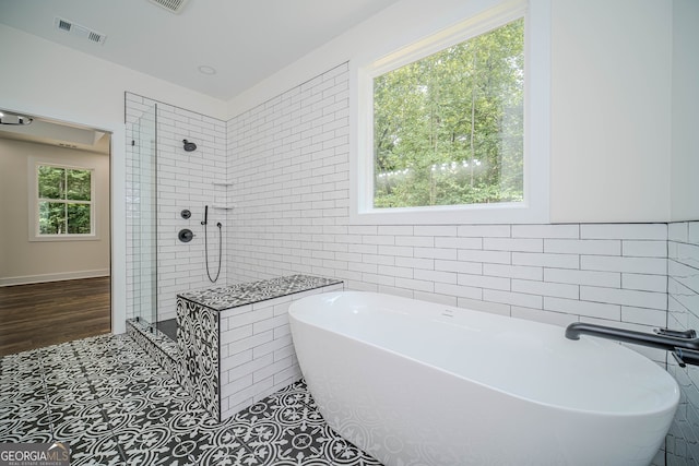 bathroom featuring tile patterned floors, independent shower and bath, and tile walls