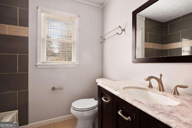 bathroom with crown molding, vanity, and toilet