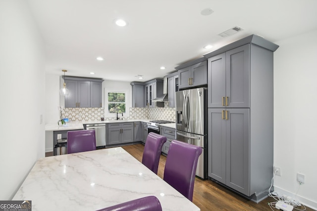 kitchen with gray cabinets, pendant lighting, sink, light stone countertops, and appliances with stainless steel finishes