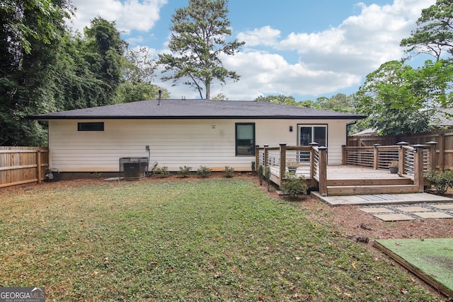 rear view of house featuring a wooden deck, a lawn, and central AC