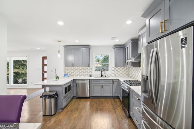 kitchen featuring pendant lighting, stainless steel appliances, dark hardwood / wood-style floors, and kitchen peninsula